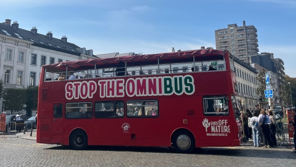 Ein roter Bus mit der Aufschrift Stop the Omnibus steht in Brüssel auf einer Straße.